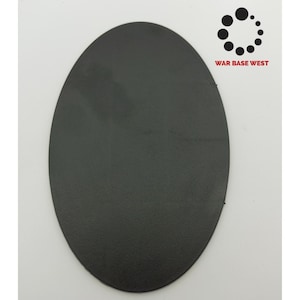 May include: A black oval-shaped plastic base for miniature figures. The base is textured and has a smooth, slightly raised edge.