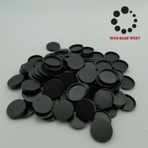 May include: A pile of black plastic round bases for miniature figures. The bases are approximately 25mm in diameter. The bases are made by War Base West.