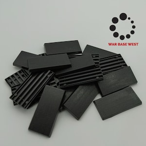 May include: A pile of black plastic rectangular tiles. The tiles have a textured surface and are used for wargaming.