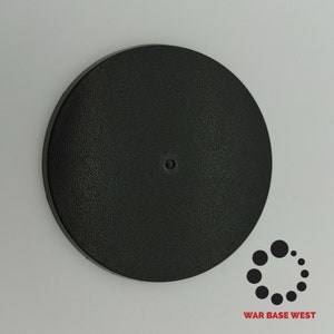 May include: A black round plastic base for miniature figures. The base has a textured surface and a small hole in the center. The base is 28mm in diameter.