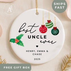 May include: A white ceramic Christmas ornament with the text "best uncle ever" and the names Henry, Emma & Chase, and the year 2025. The ornament features holly and hanging ornaments.