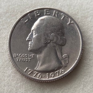 May include: A silver US quarter dollar coin with the image of George Washington on the obverse. The coin has the inscription "LIBERTY" above the image and "IN GOD WE TRUST" below the image. The date "1776-1976" is inscribed on the bottom of the coin.