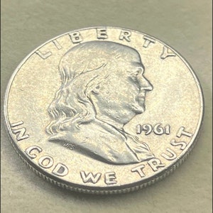 May include: Silver US half dollar coin with the profile of Benjamin Franklin and the words "LIBERTY", "IN GOD WE TRUST", and "1961".