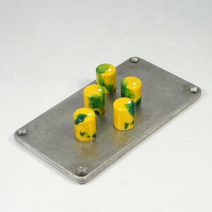 May include: Five yellow and green swirl knob buttons on a silver metal plate.