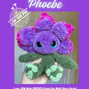 May include: A plush crochet orchid toy named Phoebe with purple and magenta petals, large blue eyes, and a dark green body with light green feet. The text reads Mini ORCHID Phoebe, LOW SEW PDF, Low-SEW Mini ORCHID from the Melt Your Heart Collection.