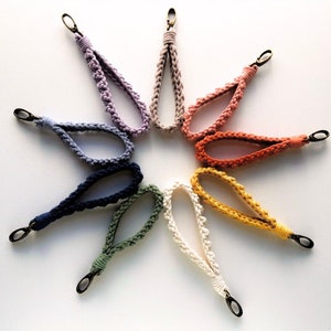 May include: A set of ten colorful crocheted keychains with metal clasps. The keychains are arranged in a star shape on a white background.