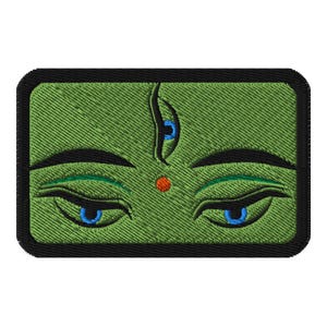 Puede incluir: Parche bordado con una representación estilizada de ojos y un tercer ojo. El diseño tiene un fondo verde con contornos negros y un borde negro. Los ojos son azules con acentos verdes, y un punto rojo está entre las cejas.