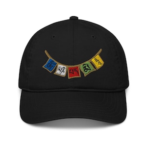 May include: Black baseball cap with an embroidered design of five colorful prayer flags with Tibetan characters. The flags are strung together in a curved line.