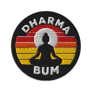 May include: A circular embroidered patch featuring a black silhouette of a person in a seated meditation pose centered against a horizontal striped background of red, orange, and yellow. The white text DHARMA BUM is stitched along the border.