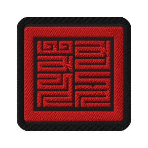 Pode incluir: Patch vermelho bordado com borda preta e um design de labirinto preto e branco no interior.