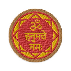 Könnte beinhalten: Ein runder, gestickter Aufnäher mit braunem Rand, gelber Mitte und rotem Innenkreis. Der Innenkreis zeigt das Sanskrit-Wort "Om" und den Satz "Hum Mati Nam:" in Hindi.