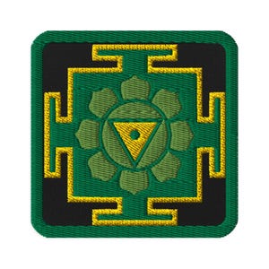 Puede incluir: Un parche bordado en verde y dorado con un símbolo estilizado de un triángulo con un punto en su interior, rodeado de un círculo de ocho pétalos. El símbolo está rodeado de un cuadrado con un borde dorado y verde.