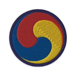 Puede incluir: Un parche circular bordado con el símbolo Taegeuk, un yin-yang rojo y azul rodeado por un círculo amarillo, todo dentro de un círculo azul marino.