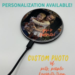 May include: A black wireless charging pad with a round, clear top. The top features a photo of two children hugging, with the text "gigi's favorite!" printed on the image. The text "CUSTOM PHOTO of pets, people favorite team or logo" is printed below the charging pad.