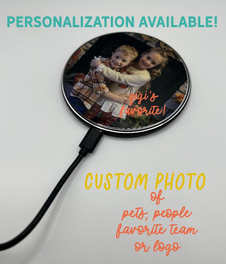 May include: A black wireless charging pad with a round, clear top. The top features a photo of two children hugging, with the text "gigi's favorite!" printed on the image. The text "CUSTOM PHOTO of pets, people favorite team or logo" is printed below the charging pad.
