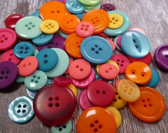 Puede incluir: Una colección de botones coloridos de diferentes formas y tamaños. Los botones están hechos de plástico y tienen un acabado liso y brillante. Los colores incluyen rojo, naranja, amarillo, verde, azul, morado y rosa.