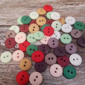 May include: A collection of colorful buttons in various shades of red, green, brown, purple, and pink. The buttons are all round and have two holes.
