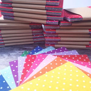 May include: Stacks of colorful felt sheets, some bundled in brown paper. Individual sheets in various colors, including yellow, orange, pink, and purple, are fanned out, each with white polka dots. The felt sheets are suitable for crafts.
