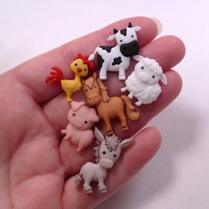Könnte beinhalten: Eine Sammlung von Miniatur-Bauernhoftierfiguren, darunter eine Kuh, ein Schaf, ein Schwein, ein Pferd, ein Esel und ein Hahn. Die Figuren sind farbenfroh und aus glänzendem Material gefertigt. Die Kuh ist schwarz-weiß, das Schaf ist weiß und das Schwein ist rosa.