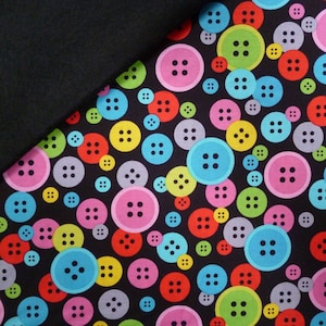 May include: Black fabric with a repeating pattern of colourful buttons. The buttons are various sizes and have a white outline.