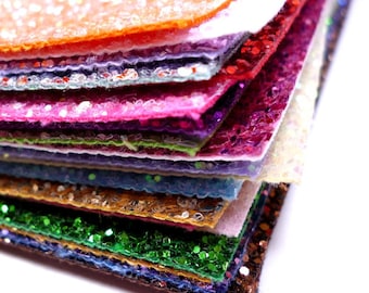 May include: A stack of colorful glitter fabric sheets in various shades of pink, purple, green, blue, orange, and brown. The sheets are stacked on top of each other, creating a layered effect.