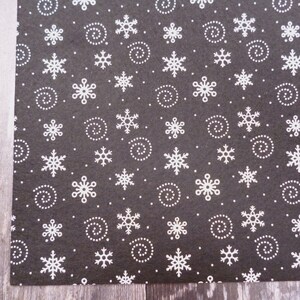 May include: Black felt fabric with a white snowflake and swirl pattern.