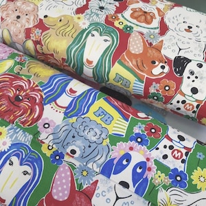 May include: Two rolls of fabric with a colourful dog pattern. The fabric features various dog breeds in a cartoon style, set against red and green backgrounds. The dogs are adorned with floral accents and the letters "FB".