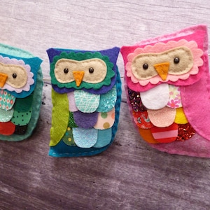 Op de afbeelding: Drie vilt uil ornamenten met kleurrijke patchwork vleugels en gezichten. De uilen zijn roze, groen en blauw.
