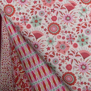 May include: Close-up of several fabric swatches with floral and geometric patterns. The fabrics feature a variety of colors, including red, pink, green, and cream. The floral pattern includes stars and stylized flowers. The geometric pattern is a diamond design.