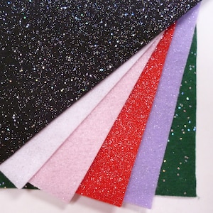 May include: A set of six glitter fabric sheets in various colours, including black, white, pink, red, purple, and green. The sheets are arranged in a fan shape, with the black sheet at the top and the green sheet at the bottom.