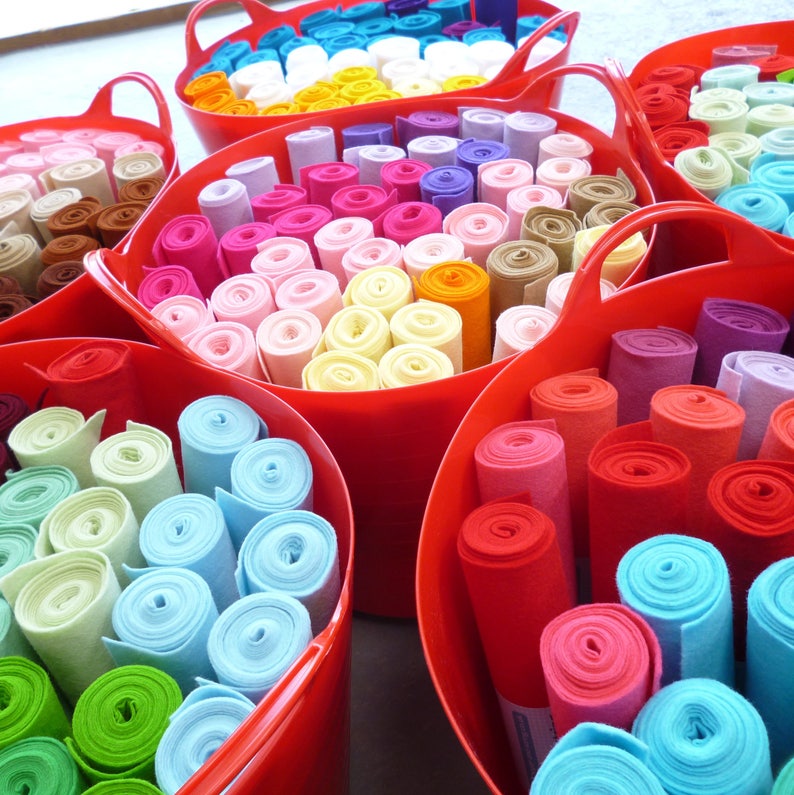 May include: Assortment of colorful felt rolls in various sizes and colors, stored in red plastic containers. The rolls are arranged in a circular pattern, creating a visually appealing display.