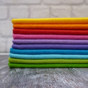 May include: A stack of ten felt fabric squares in various colours, including yellow, orange, red, pink, purple, blue, turquoise, and green.