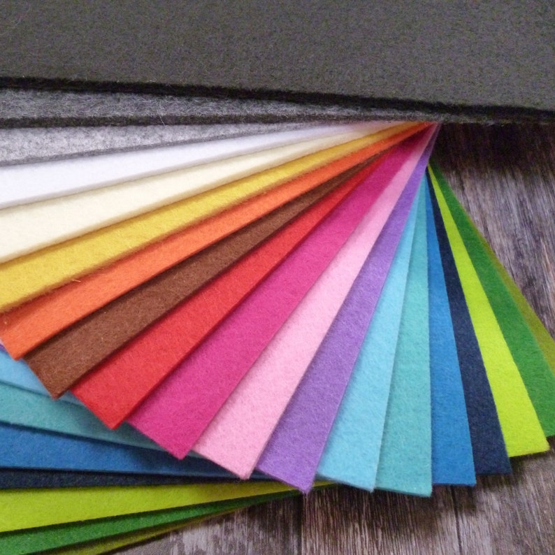 Puede incluir: Un abanico de fieltro de varios colores, incluyendo negro, blanco, amarillo, naranja, rojo, rosa, morado, azul, verde y marr&oacute;n. El fieltro est&aacute; dispuesto en forma de abanico, con los colores m&aacute;s oscuros en la parte superior y los colores m&aacute;s claros en la parte inferior.