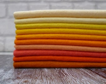 May include: A stack of 10 felt sheets in various shades of orange, yellow, and cream. The felt is arranged in a gradient from light cream to dark orange.