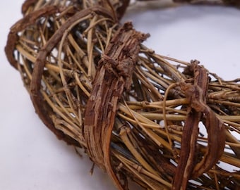 Può includere: Una ghirlanda di rami marroni con un design intrecciato. La ghirlanda è realizzata con materiali naturali e ha un aspetto rustico.