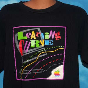 May include: Black t-shirt with a colorful graphic of a computer and the text "Learning Curve". The graphic also includes a rainbow colored pencil and the Apple logo.