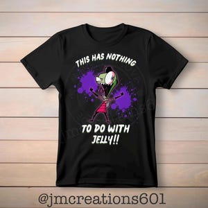 May include: Black t-shirt featuring a cartoon character with green skin, a red outfit, and purple energy blasts. The text "THIS HAS NOTHING TO DO WITH JELLY!!" is printed above the character. The shirt has short sleeves.