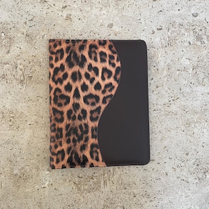 May include: A brown and leopard print binder with a black leather flap.