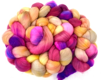 May include: A braided bundle of colorful wool yarn in shades of pink, purple, yellow, and orange. The yarn is arranged in a circular shape, creating a visually appealing display.