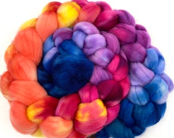 May include: A braided bundle of colorful wool yarn in shades of orange, yellow, pink, purple, and blue. The yarn is arranged in a spiral pattern.