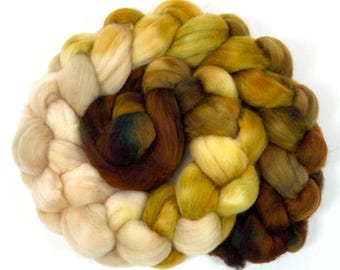 Puede incluir: Un manojo de hilo trenzado en tonos beige, marrón y amarillo. El hilo está dispuesto en forma circular, con los extremos de la trenza metidos en el centro.