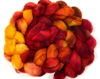 May include: A braid of red, orange, and yellow wool roving. The roving is arranged in a circular shape, with the ends of the braid tucked in.