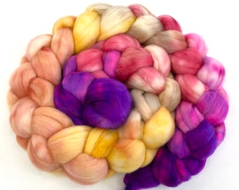 May include: A braided bundle of colorful wool yarn in shades of purple, pink, yellow, and beige.