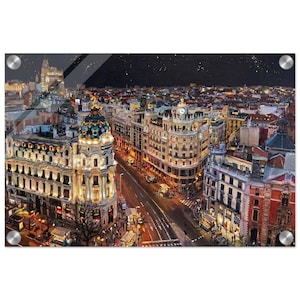 May include: A cityscape print of Madrid at night, featuring illuminated buildings and streets. The artwork showcases a detailed view of the city's architecture, with a dark sky and visible stars. The print is mounted on a clear acrylic panel with silver hardware.