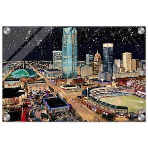 May include: An acrylic print of a nighttime cityscape featuring illuminated skyscrapers, a baseball stadium, and a domed arena. The artwork has a dark night sky with white star-like accents and is mounted with silver hardware.
