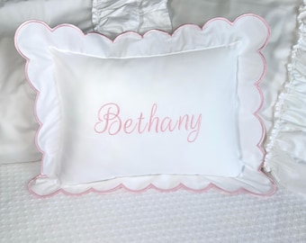 Puede incluir: Almohada rectangular blanca con borde festoneado rosa. El nombre "Bethany" está bordado en rosa en el centro. La almohada está sobre una colcha blanca. Ideal para un dormitorio.