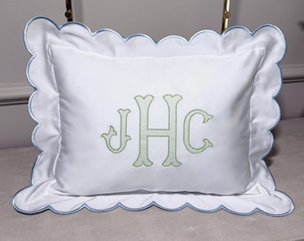 May include: White rectangular pillow with a scalloped edge and a light blue trim. The pillow features an embroidered monogram in light green. The monogram includes the letters JHC.