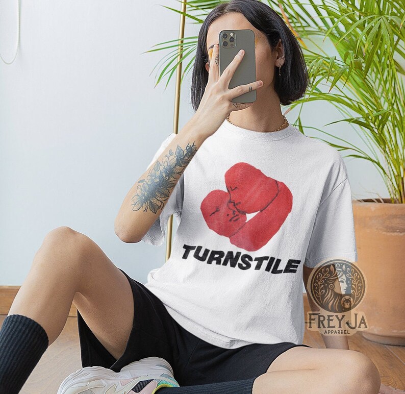 May include: White t-shirt with a red graphic of two boxing gloves in a heart shape. The text "TURNSTILE" is printed in black below the graphic.