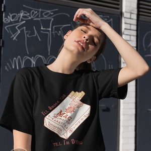 May include: Black t-shirt with a graphic of a pack of cigarettes with the text "I'll smoke you 'til I'm dying" and the brand name "Mac Cigarettes Pitchfork Records".