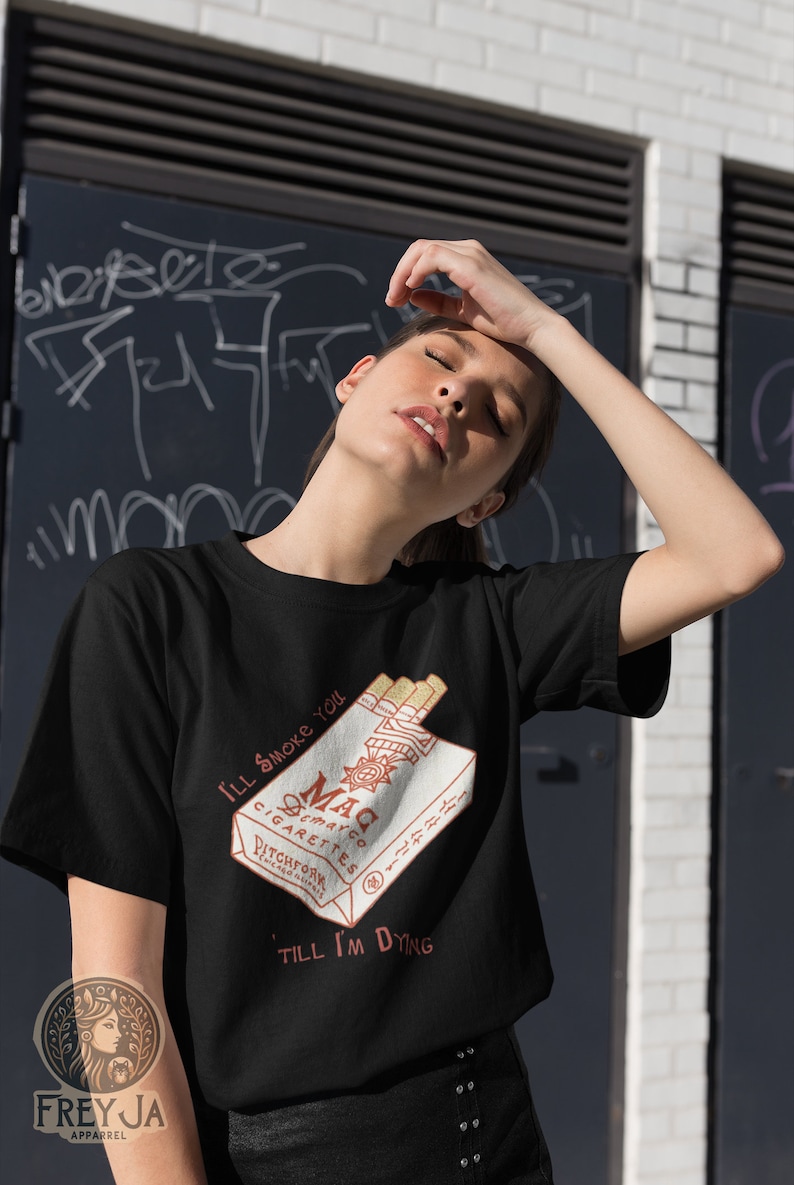 May include: Black t-shirt with a graphic of a pack of cigarettes with the text "I'll smoke you 'til I'm dying" and the brand name "Mac Cigarettes Pitchfork Records".